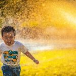 Happy Family Sunlight - a young boy running through a sprinkle of water