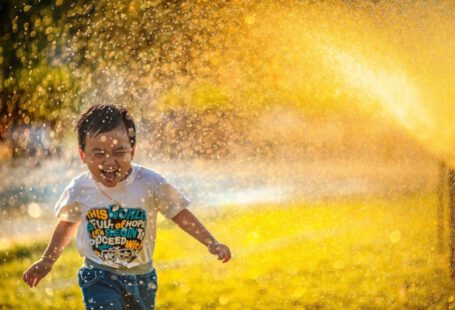 Happy Family Sunlight - a young boy running through a sprinkle of water